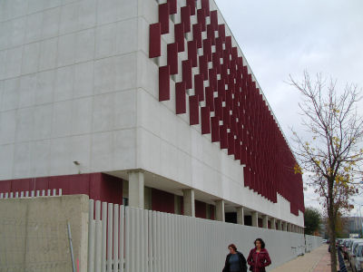 会場となったセビリア大学コミュニケーション学部の建物の外観。白く平らな壁に，赤い長方形の板が多数張り付けられている。